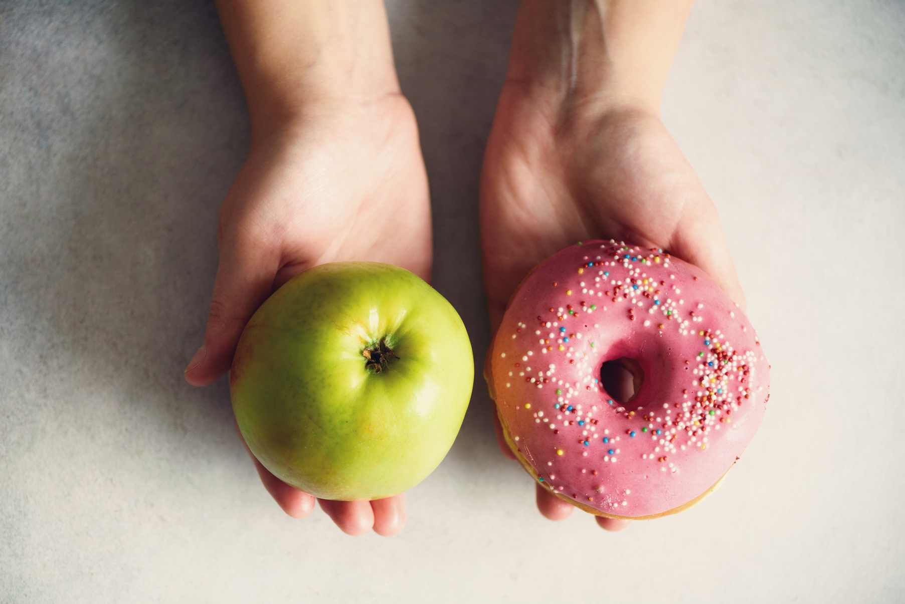 Hands Holding a Doughnut and Apple 